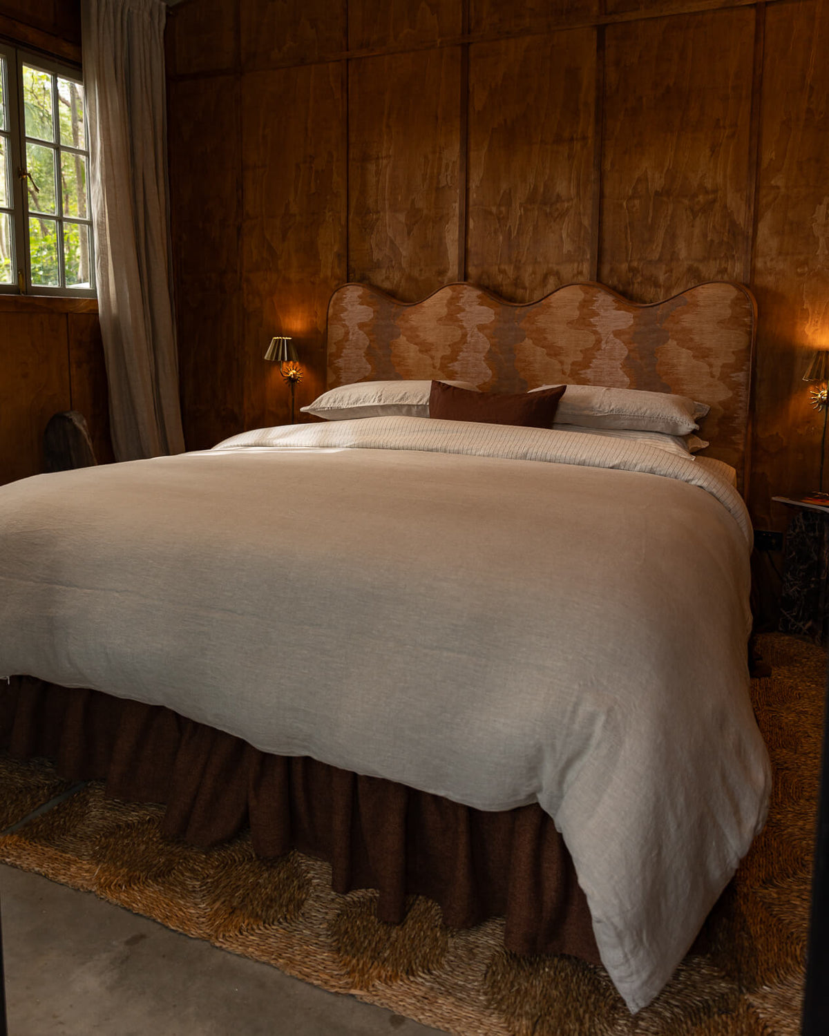 NESTD luxury flax linen bedding featuring Canyon and Dune white layers, styled with matching pillows and a draped duvet against a warm textured headboard.