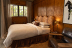 NESTD luxury flax linen bedding featuring rich Sable brown and Dune white layers, styled with matching pillows and a draped duvet against a warm textured headboard.