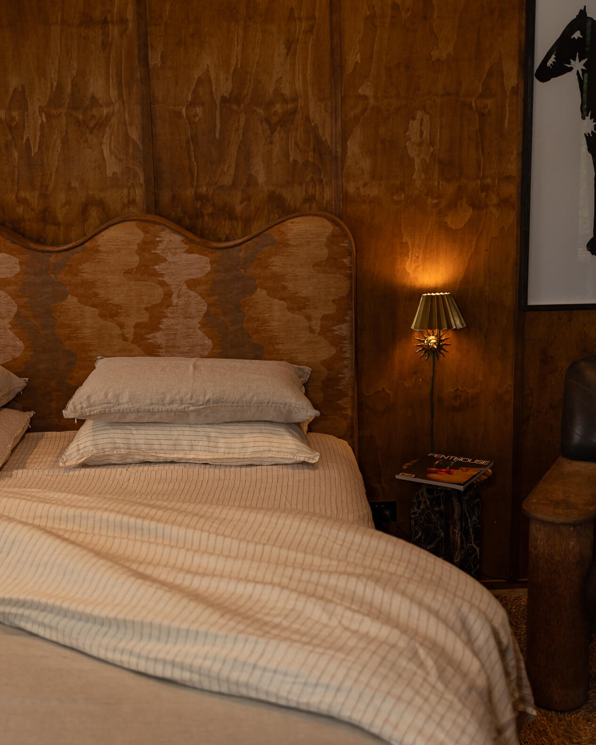 NESTD luxury flax linen bedding in Canyon Stripe white and Dune tones, featuring layered pillows and a neatly folded duvet against a textured headboard.
