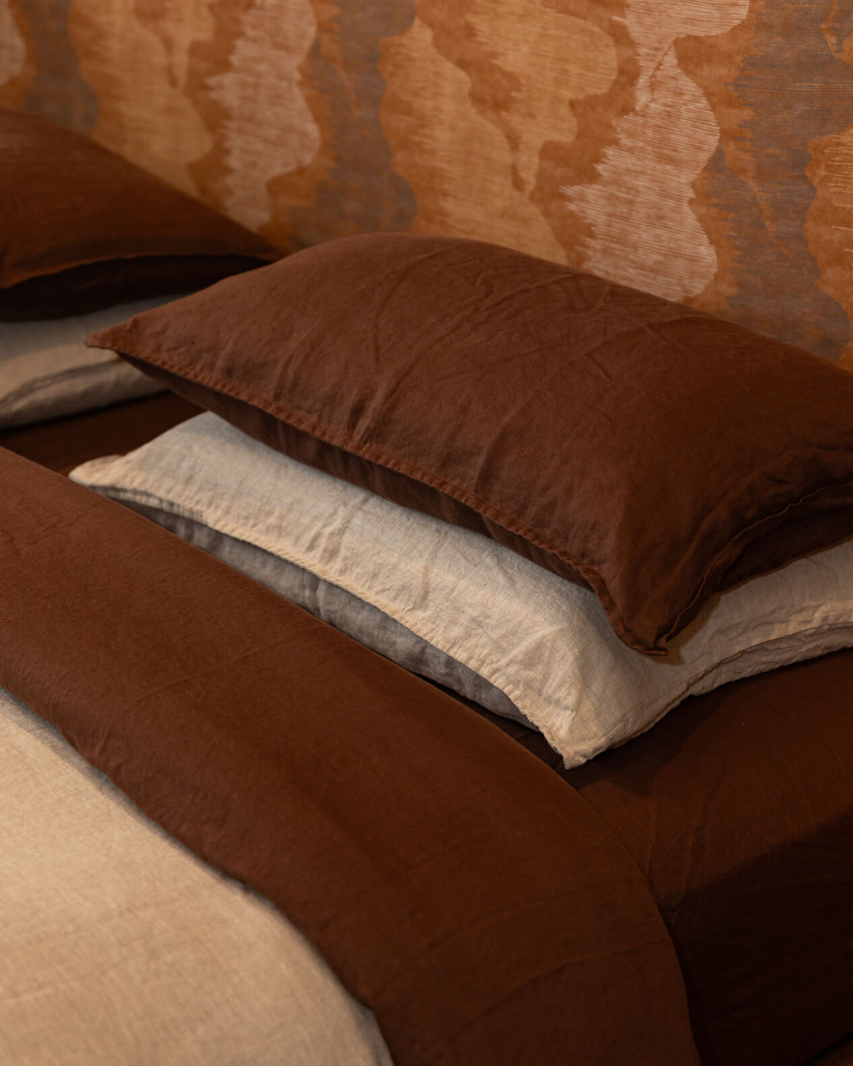 Stack of sable and dune pillows on a textured surface