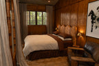 Cozy bedroom with wooden walls and a NESTD luxury flax linen bedding featuring rich Sable brown and Dune layers, styled with matching pillows and a draped duvet against a warm textured headboard.