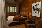 Cozy bedroom with wooden walls and a NESTD luxury flax linen bedding featuring rich Sable brown and Dune layers, styled with matching pillows and a draped duvet against a warm textured headboard.